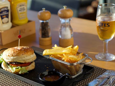 Burger with fries, beer and other condiments on the table
