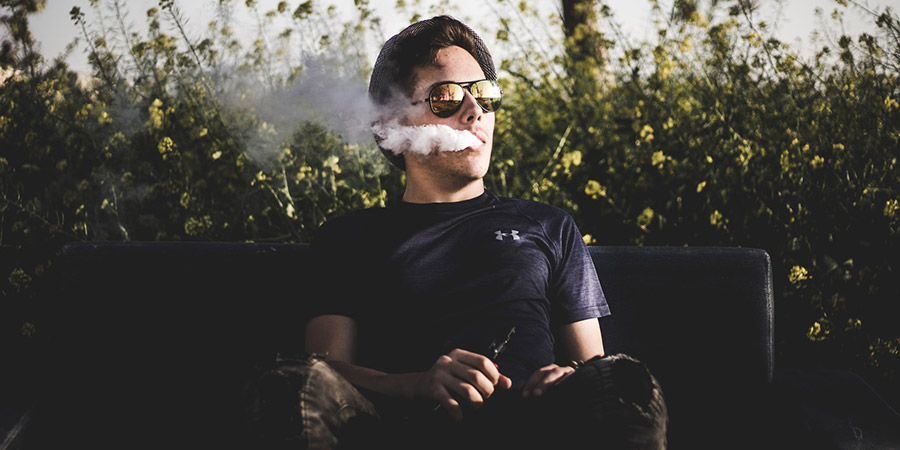man vaping and sitting on a bench